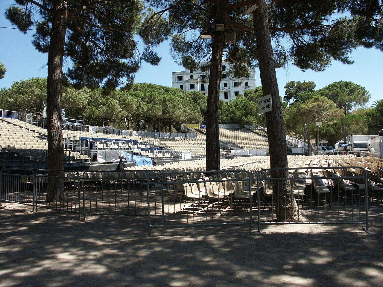 La pinède Gould l'après-midi d'un concert, avec les rangées de chaises devant la scène et les tribunes au fond, sous les pins
